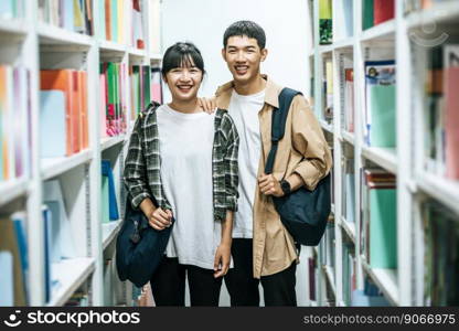 Men and women carrying a backpack and searching for books in the library.