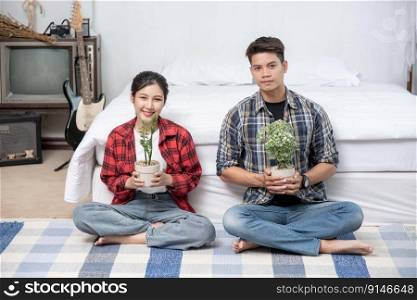 Men and women sit and holding plant pots in the house.