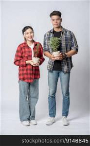 Men and women standing and holding plant pots in the house.