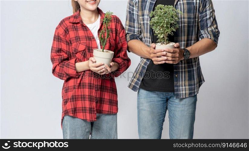 Men and women standing and holding plant pots in the house