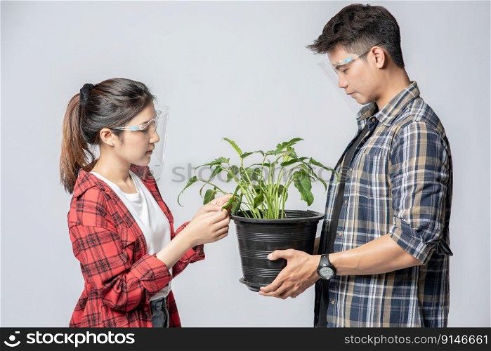 Men and women standing and holding plant pots in the house.
