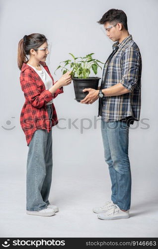 Men and women standing and holding plant pots in the house.