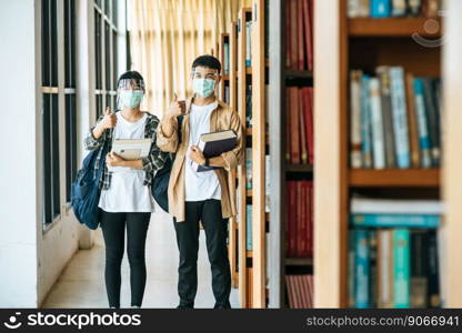 Men and women wear masks to stand, hold books in the library and put their thumbs up.