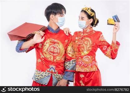 Men and women wear Qipao and wear face masks, carry paper bags, go shopping with credit cards.