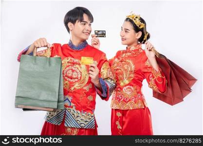Men and women wear qipao, carry paper bags, go shopping with credit cards.
