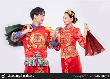 Men and women wear qipao, carry paper bags, go shopping with credit cards.