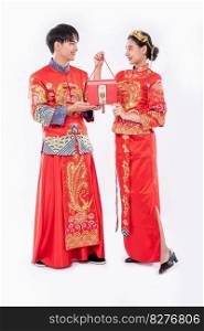 Men and women wearing cheongsam standing with red bags