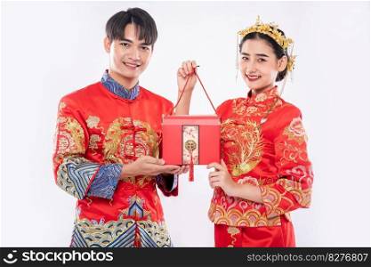 Men and women wearing cheongsam standing with red bags