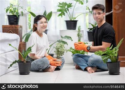 Men and women wearing orange gloves sat and planted trees in a house.