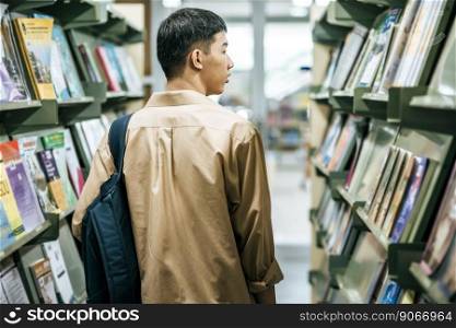 men carrying a backpack and searching for books in the library.