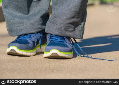 men feet in sneakers with untied lace