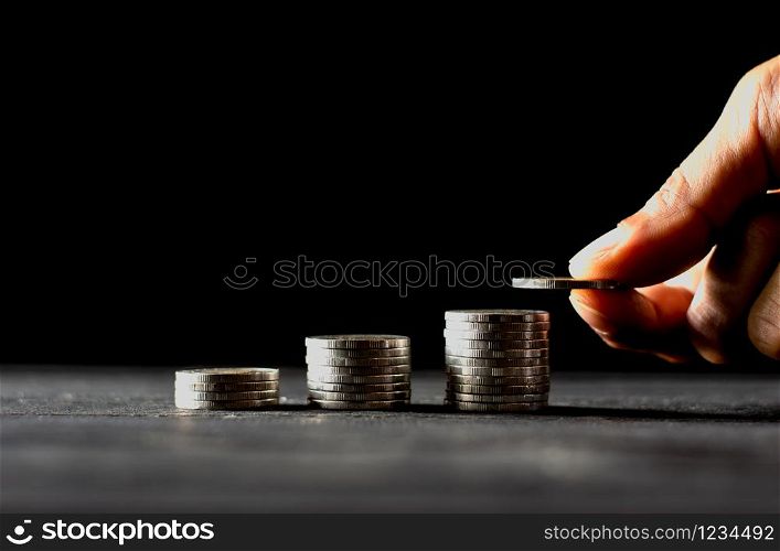 Men hand are sorted coins on a black wooden board, dark tone.