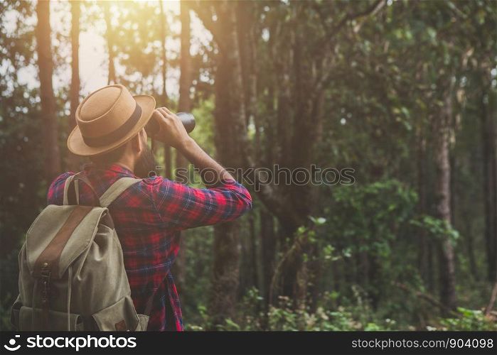 Men have a beard shining a distance camera while hiking.