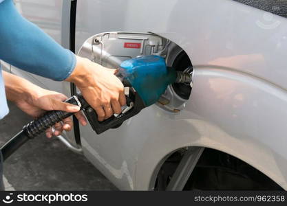 Men hold Fuel nozzle to add fuel in car at gas station