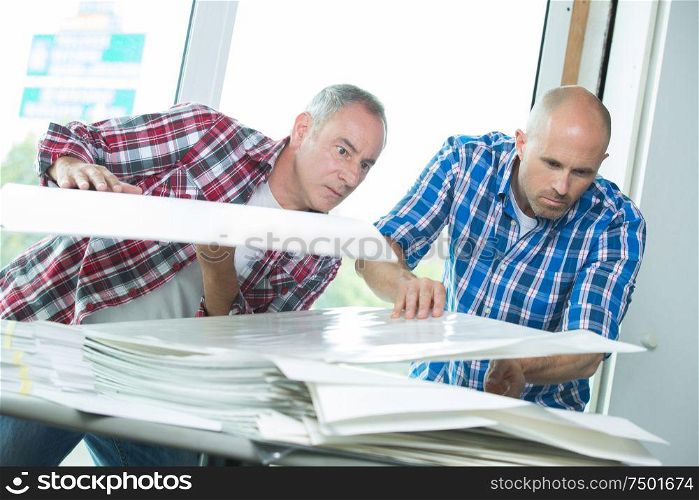 men in printing business looking through plastic copies