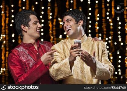 Men laughing at sms on mobile phone