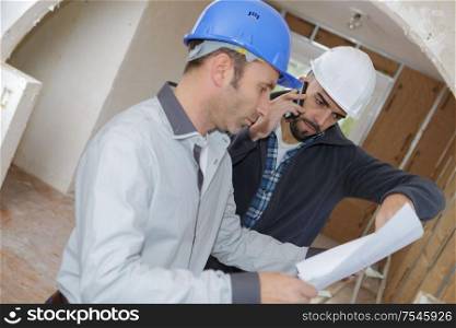 men on indoor worksite looking at plans