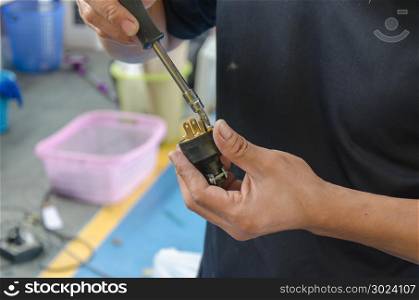 Men repairing a socket with a screwdriver
