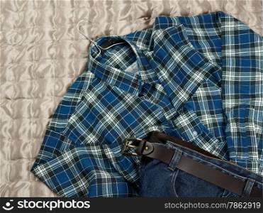 Men&rsquo;s casual checkered shirt and jeans on the bed