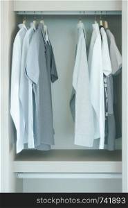 Men's cloths hanging in white wardrobe