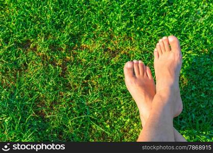 Men&rsquo;s feet on the background of lush green grass