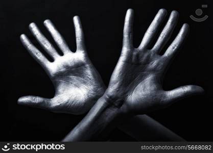 Men&rsquo;s hand in a silver paint isolated on black background&#xA;