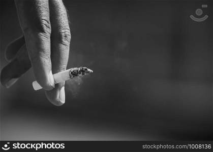 Men's hand is picking up cigarettes, black and white tone.