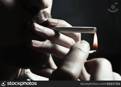 Men&rsquo;s hand lights a cigarette with a match closeup