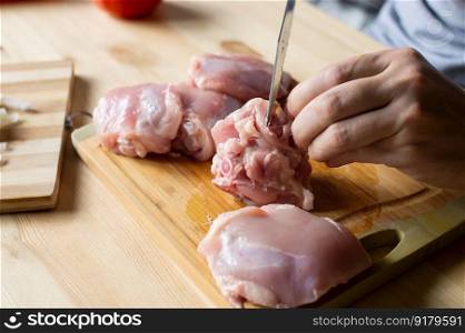 Men&rsquo;s hands are cutting chicken meat on a cutting board. Men&rsquo;s hands butcher poultry meat