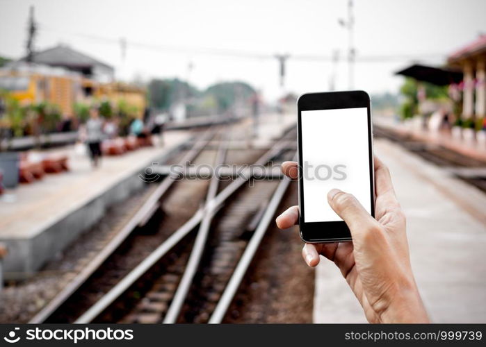 Men's hands are holding a smartphone at the train station, mockup phone concept, technology and transportation.