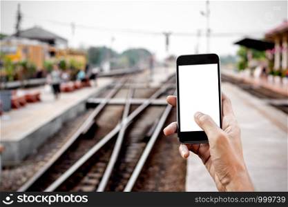 Men's hands are holding a smartphone at the train station, mockup phone concept, technology and transportation.