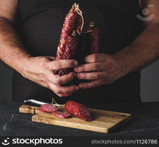 Men&rsquo;s hands hold different types of salami