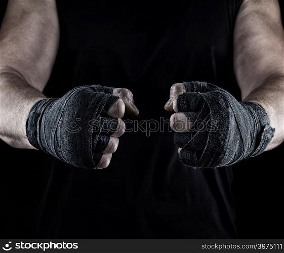 men&rsquo;s hands wrapped in a black bandage, body parts in front of the torso, black background