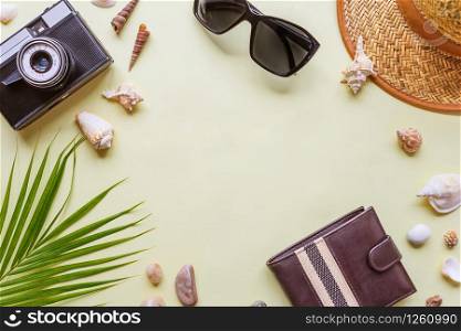 Men&rsquo;s traveler accessories: green tropical palm leaf, photo camera, seashells and sunglasses are on yellow background with copy-space. Top view travel or vacation concept, flat lay summer background