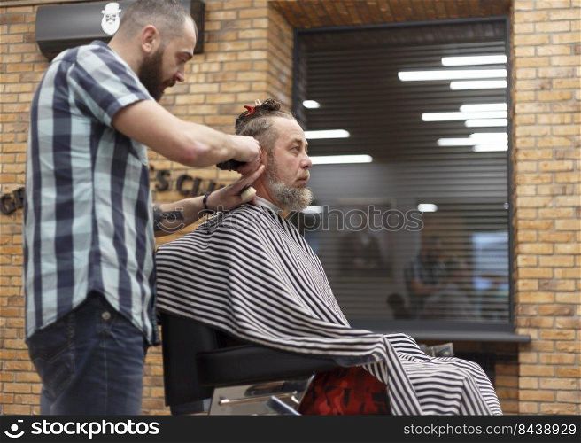 Men"s hairstyling and haircutting with hair clipper in a barber shop or hair salon. Shallow depth of field. 