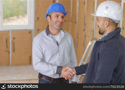 Men shaking hands on indoor building site