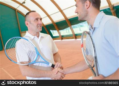 Men shaking hands on tennis court