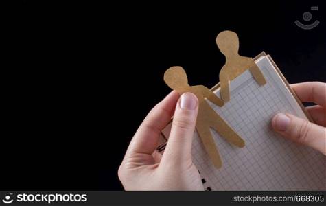 Men shape cut out of paper in notebbok in hand