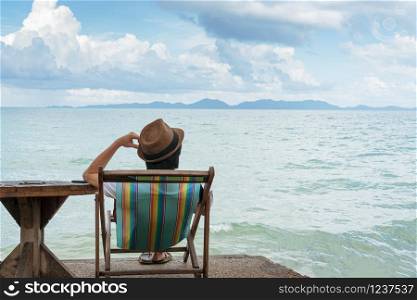 Men sitting on beach chair while using mobile phone, Copy space.