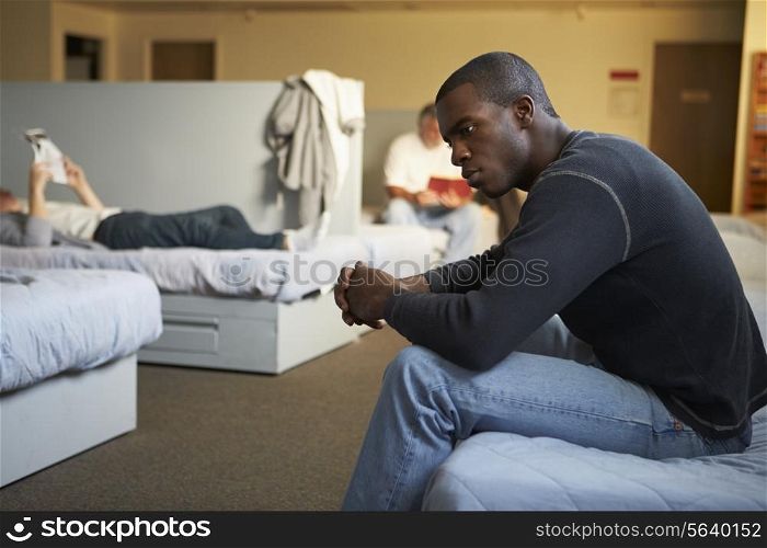 Men Sitting On Beds In Homeless Shelter