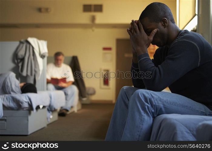 Men Sitting On Beds In Homeless Shelter
