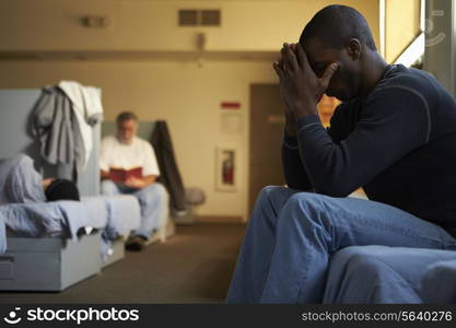 Men Sitting On Beds In Homeless Shelter