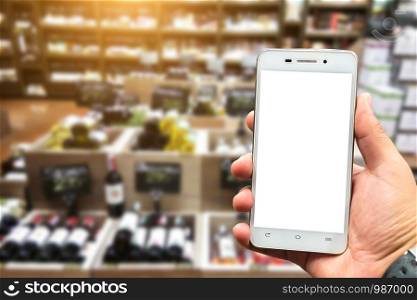 Men use hold smartphone blurred images of Various alcohol bottles in a row at the spirits store background.