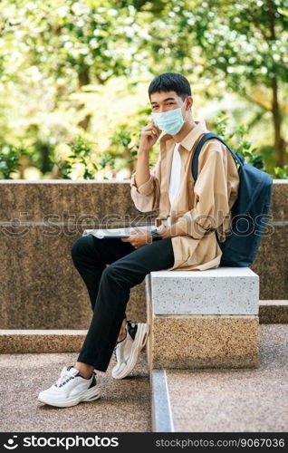 Men wearing masks sit reading books on the stairs.