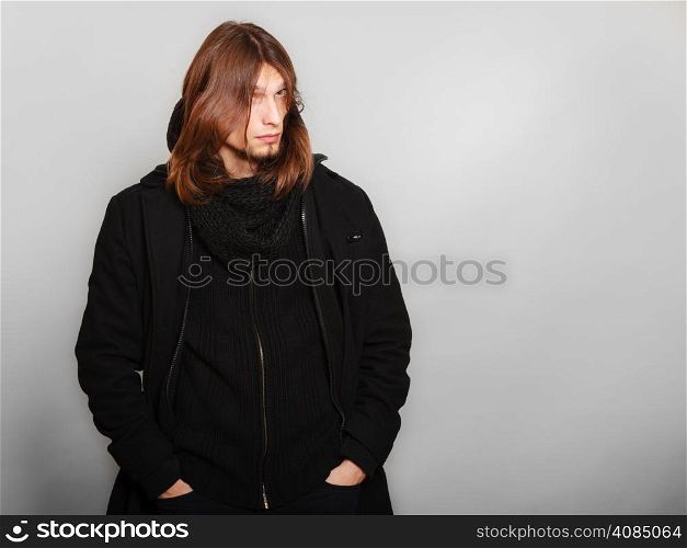 Men winter fashion. Handsome man long hair wearing black coat. Casual look. Studio shot on grey
