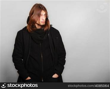 Men winter fashion. Handsome man long hair wearing black coat. Casual look. Studio shot on grey