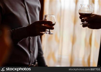 men with a friend standing by the window. hold in the hands of glasses of whiskey.. men with a friend standing by the window. hold in the hands of glasses of whiskey. close up