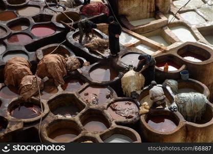 Men working in the Chouara Tannery in the middle of souk in Fez, Morocco. Traditional leather tannery from the 11th century is now biggest tourits attraction in Fes.. Old tannery in Fez, Morocco