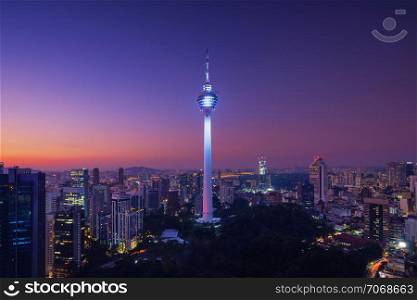 Menara Kuala Lumpur Tower at night. Aerial view of Kuala Lumpur Downtown, Malaysia. Financial district and business centers in urban city in Asia. Skyscraper and high-rise buildings at noon.