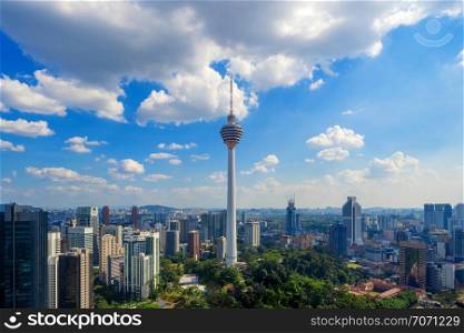 Menara Kuala Lumpur Tower with clouds sky. Aerial view of Kuala Lumpur Downtown, Malaysia. Financial district and business centers in urban city in Asia. Skyscraper and high-rise buildings at noon.